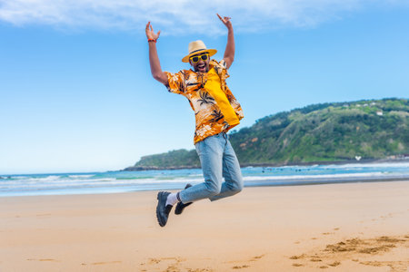 Full length photo of an African American man jumping on the beachの写真素材