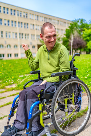 Vertical exterior portrait of a disabled man smiling sitting in the electric wheelchair in the university campusの写真素材