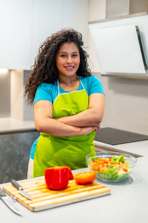 Vertical portrait of a latin young happy vlogger standing proud in the kitchen preparing healthy foodの写真素材