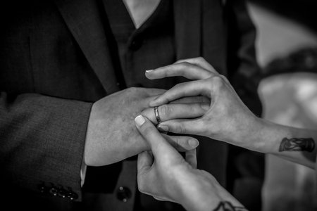 A man and woman are getting married and the man is putting a ring on the woman's fingerの写真素材