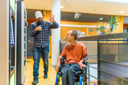 Man with disability and colleague chatting next to vending machine in a modern coworkingの写真素材