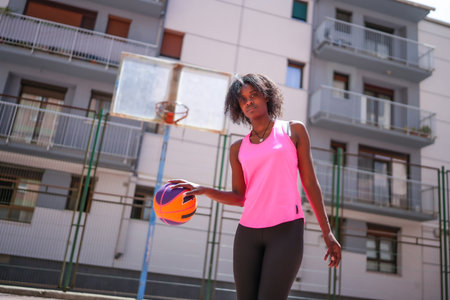 Low angle view portrait of a confident african woman playing basketball outdoorsの写真素材