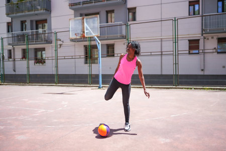 Full length photo of a young sportive african woman stretching in a basketball courtの写真素材