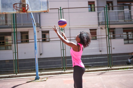 Young african woman throwing basketball ball in an outdoor urban courtの写真素材