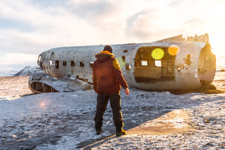 Selfie of a tourist man with his back turned on the crashed plane on the frozen Solheimasandur beach in winter, Icelandの写真素材