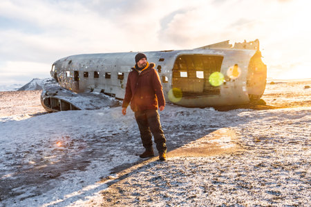 A tourist man walking on the crashed plane on the frozen Solheimasandur beach in winter in Icelandの写真素材