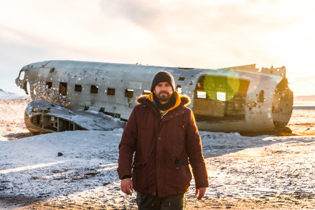 A tourist man walking on the crashed plane on the frozen Solheimasandur beach in winter in Icelandの写真素材