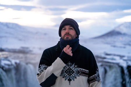 Portrait of an adventurous hiker at the frozen Godafoss waterfall in winter, Icelandの写真素材
