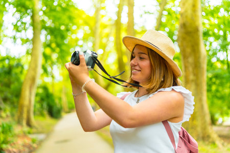 Close up side view of a caucasian young cheerful woman hiking in the forest with cameraの写真素材