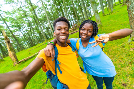 African young male and female friends having fun taking in selfie in the forestの写真素材