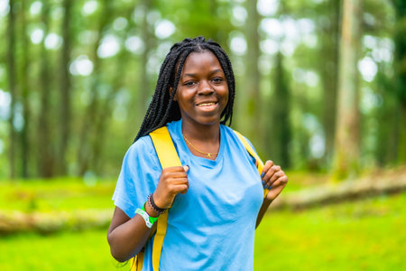 Portrait of a happy young african woman hiking through green forestの写真素材