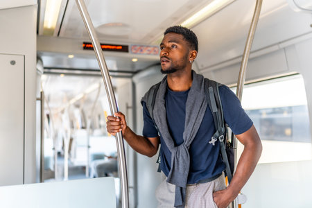 Cheerful and confident african young man traveling by metro along the cityの写真素材