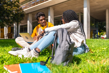 Side view of two male and female african students using laptop studying together on the campusの写真素材
