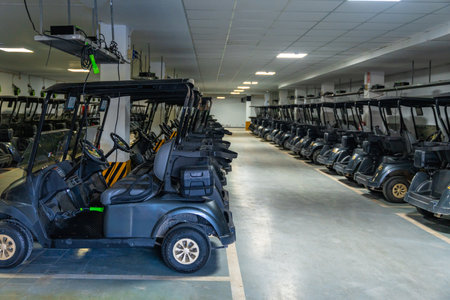 Full length horizontal photo of a line of golf carts parked in a garageの写真素材