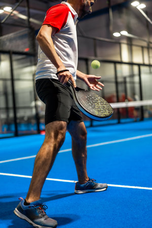Vertical photo of a mature caucasian man serving while playing paddle tennis with friendsの写真素材