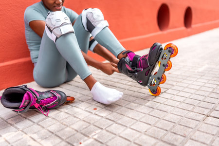 Cropped photo of part of an unrecognizable woman putting on inline skates sitting on the street
