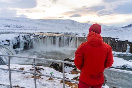 A man with his back turned at the beautiful Godafoss waterfall in winter in Iceland.の写真素材