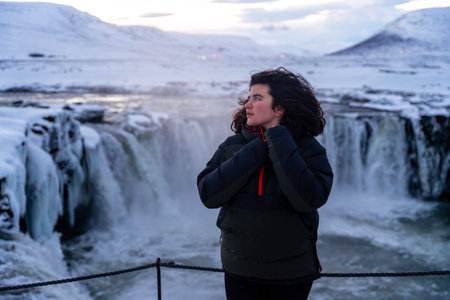 Portrait of a woman at the beautiful Godafoss waterfall in winter in Iceland.の写真素材