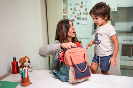A woman is helping a young boy open his backpack.の写真素材