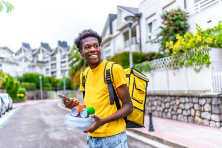 Delivery african man with food and beverage in hands on duty in the cityの写真素材