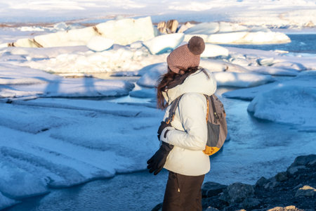 A woman with her back turned looking at the frozen iceberg lake of Jokursarlon. Icelandの写真素材