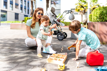 Full length photo of a happy woman and sons playing with toys in an urban spaceの写真素材