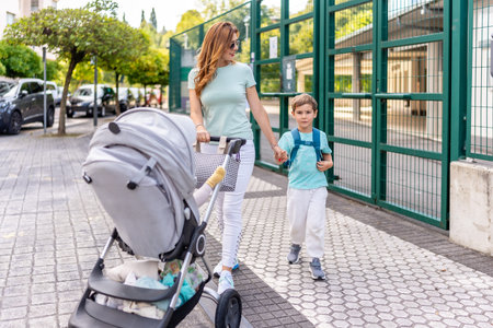 Mother pushing baby carriage and boy going back home after my first day at school