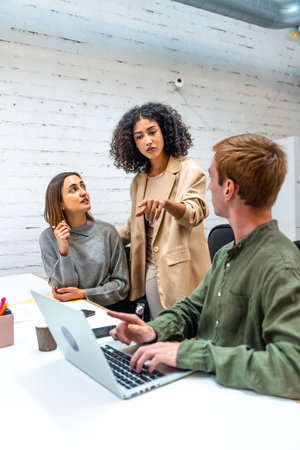 Vertical photo of a hispanic female boss discussing with two employees in a coworking spaceの写真素材