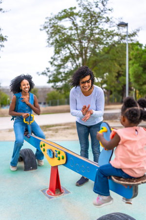 African young mother and grandmother encouraging a little girl in the playgroundの写真素材