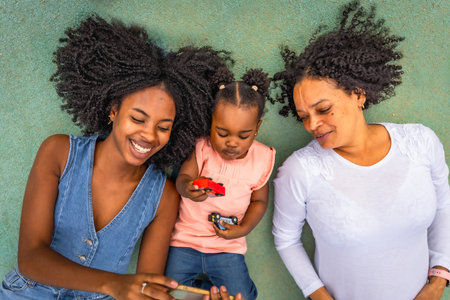 Multi-generation African woman lying using mobile and playing in the park. family conceptの写真素材