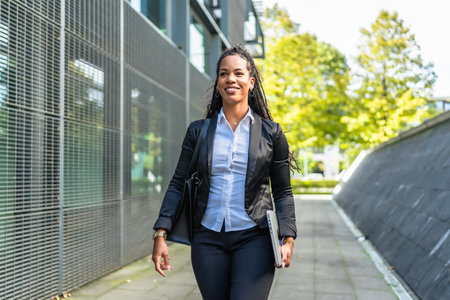 Real estate agent latin woman walking outside building holding laptopの写真素材