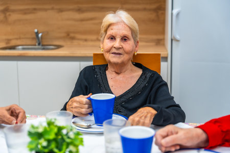 Senior woman smiling eating breakfast in the nursing home sitting on the dining room in a shared tableの写真素材