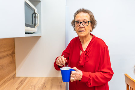 Portrait of a distracted senior woman heating coffee in the microwave in the geriatricsの写真素材