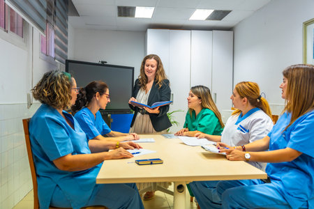Team of female caucasian health workers sitting meeting room during work meeting at geriatricsの写真素材