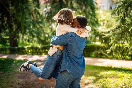 Multi-ethnic couple in love embracing and jumping together in a parkの写真素材