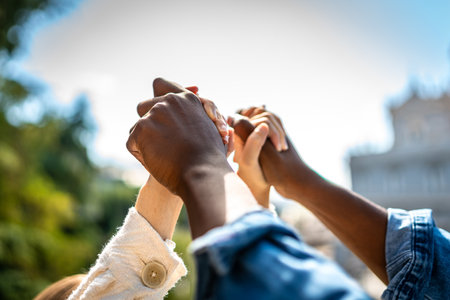 Cropped photo of the hands of a multiracial couple holding hands in air in a parkの写真素材