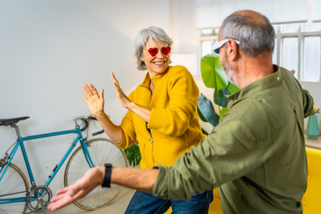 Modern senior couple with stylish sunglasses having fun together at home laughing and dancingの写真素材
