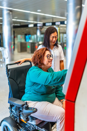 Vertical side view photo of a disabled woman and friend buying the ticket for the metroの写真素材