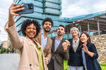 African businesswoman taking selfie with multi-ethnic coworkers in the street next to modern financial buildingの写真素材