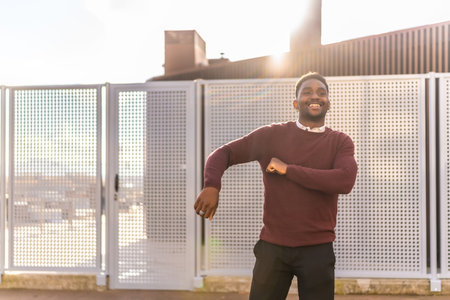 Three quarter length frontal photo of a happy african man in casual clothes dancing in the city on a...