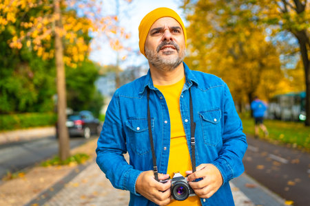 Frontal portrait of a male mature tourist gazing the city while holding digital cameraの写真素材