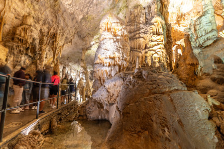 Tourists observing the magnificent stalactites and stalagmites formations inside postojna cave, a famous tourist attraction in Sloveniaの写真素材