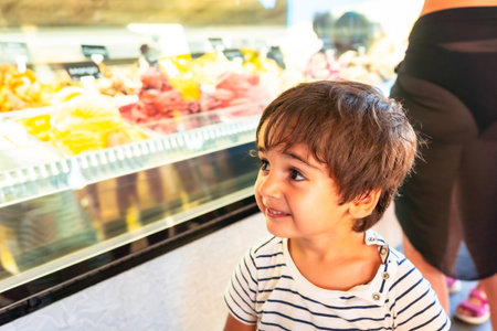 Happy toddler choosing ice cream from a refrigerated display case in a gelateria in Piran, Sloveniaの写真素材