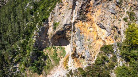 Majestic rinka waterfall flows down rocky cliffs into the lush green Logarska dolina valley, creating a breathtaking natural wonder in the Slovenian Alpsの写真素材