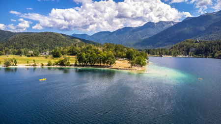 Aerial view of tourists enjoying summer holidays, swimming and kayaking on the beautiful lake Bohinj, surrounded by the Julian Alps in Sloveniaの写真素材