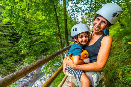 Mother holding her son while wearing helmets and enjoying the breathtaking scenery of Vintgar Gorge in Bled, Sloveniaの写真素材