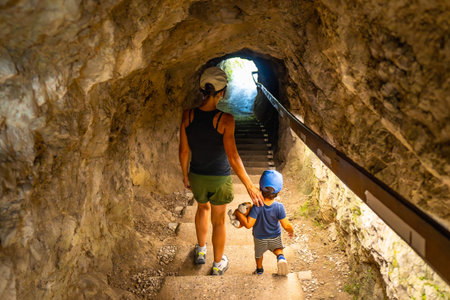 Mother and son walking up the stairs in a tunnel carved into the rock face at Tolmin Gorge in Sloveniaの写真素材
