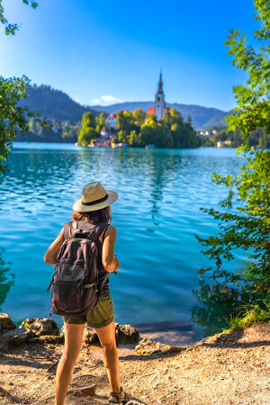 Female tourist admiring the beautiful landscape of lake Bled in Slovenia with the church on a small islandの写真素材