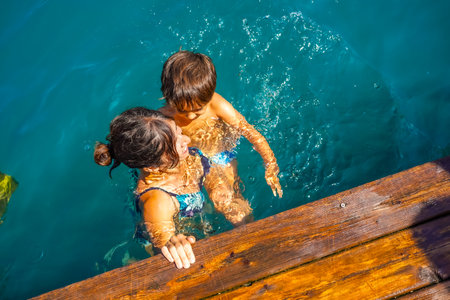 Mother and son having fun swimming in the turquoise water of lake Bled, a popular tourist destination in the Julian Alpsの写真素材