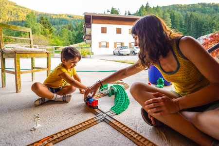 Mother and son enjoying quality time together, playing with a toy train set during their summer vacation in a mountain settingの写真素材